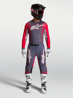 Maillot Alpinestars Supertech Hiten AFD, maillot de motocross pour homme, gris et rouge fluo, coupe athlétique avec mesh ventilé, porté avec équipement complet.