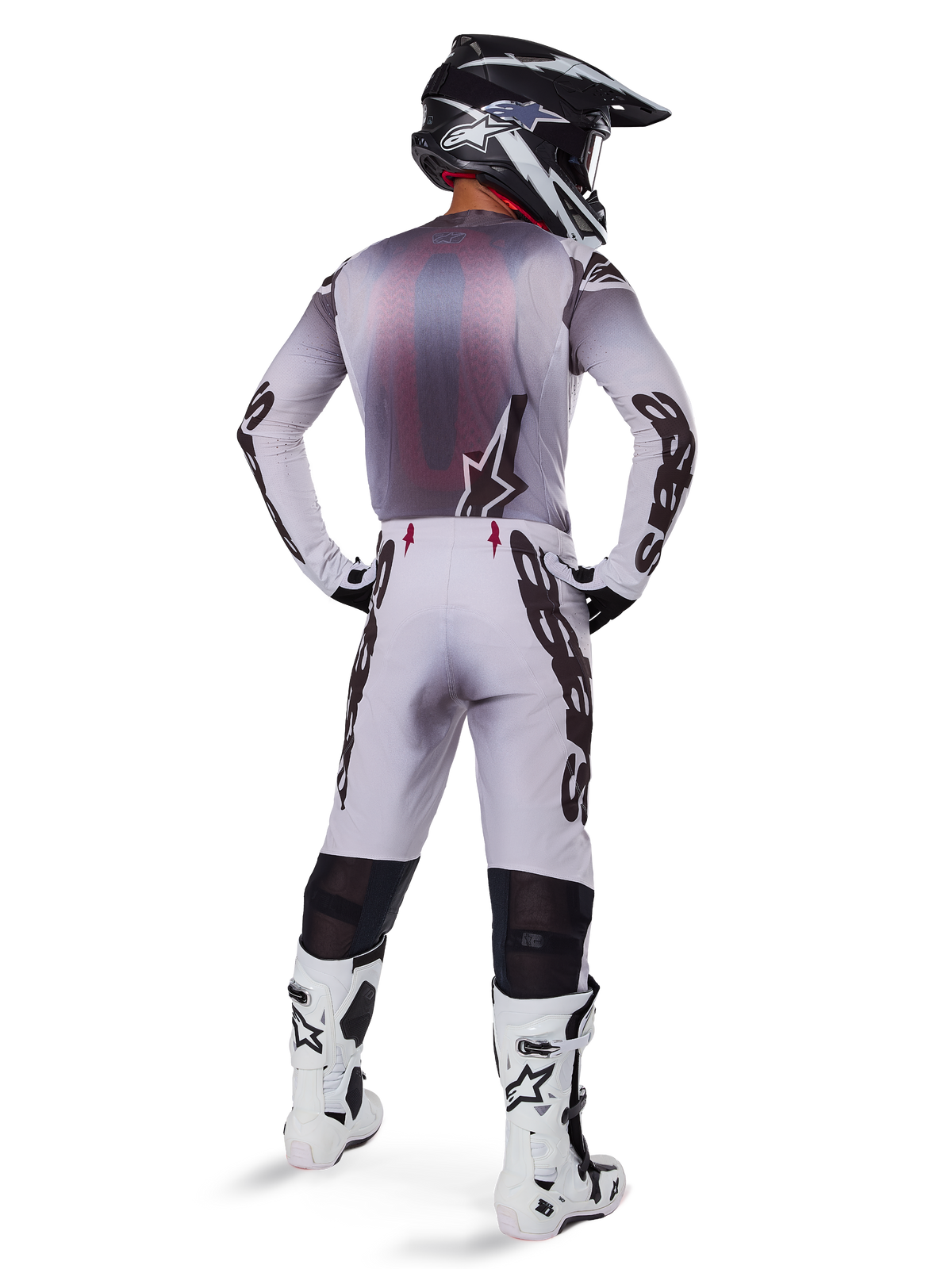Maillot Alpinestars Supertech Maker 2025, maillot de motocross, argent et noir, vue arrière d'un pilote portant une tenue assortie et des bottes blanches, avec marquage Alpinestars sur les manches et logo étoilé dans le dos, coupe de course athlétique pour des performances professionnelles en tout-terrain