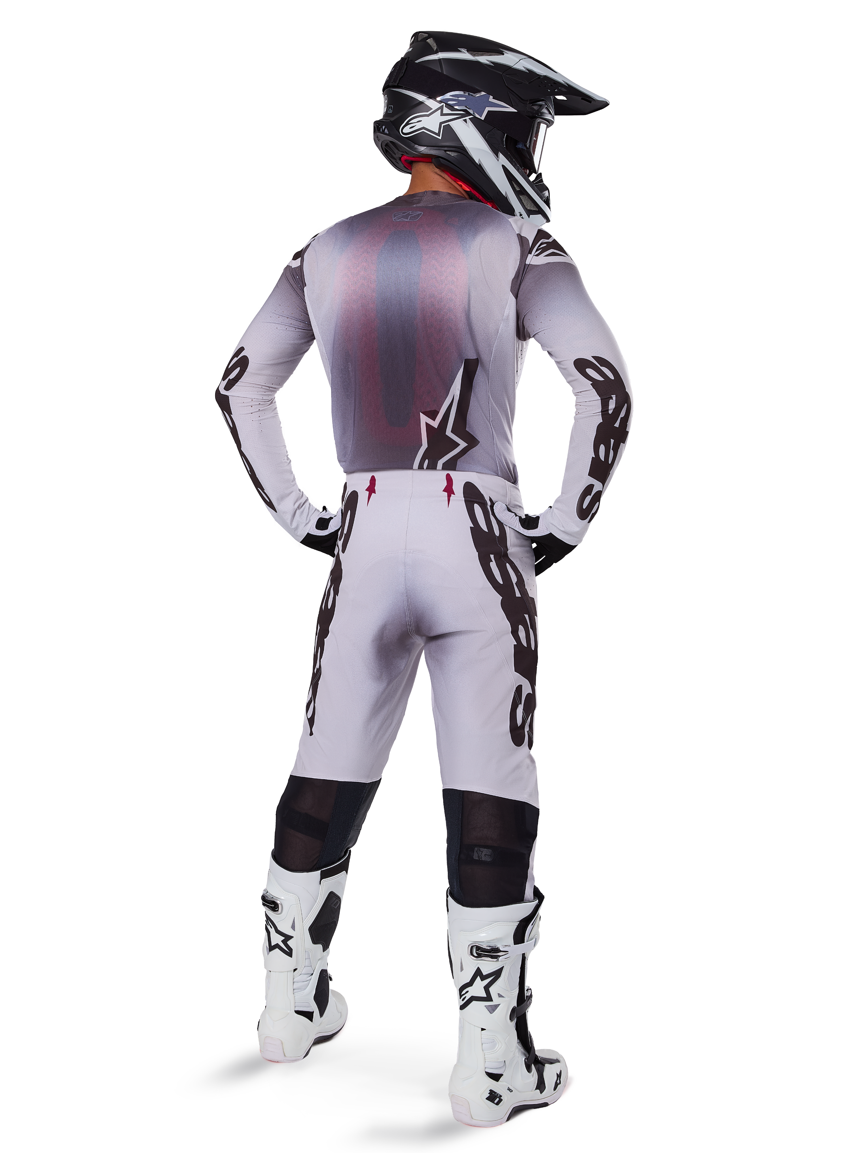 Motocross rider wearing complete racing gear, grey and black jersey, light grey pants with black 'Astars' branding on the sides, black and white helmet, White Tech 10 Boots, coordinated professional off-road racing outfit
