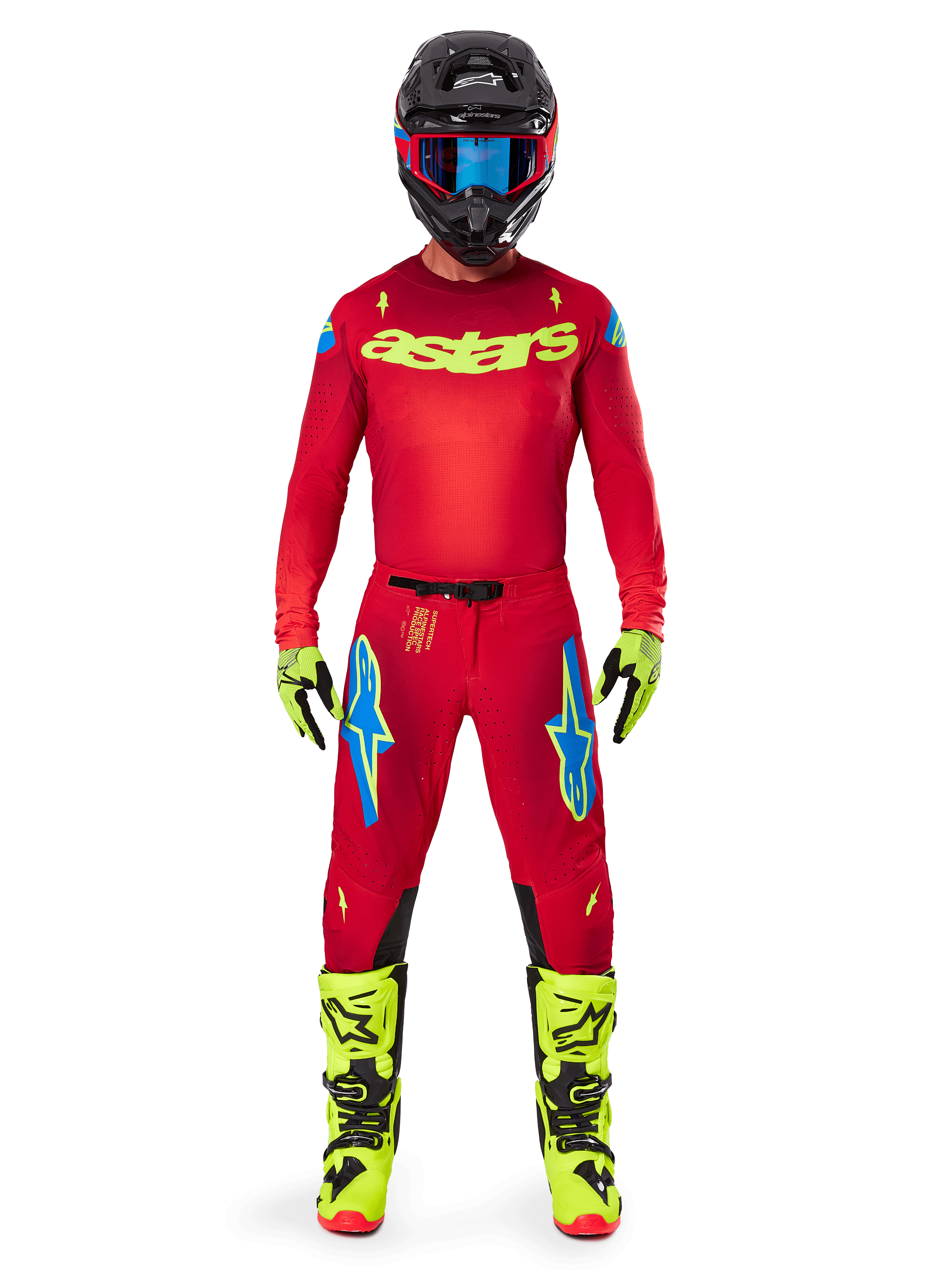 Pilote de motocross portant l'ensemble d'équipement complet Alpinestars 2025 Supertech Maker, maillot rouge vif avec logo 'astars' jaune fluo, pantalon rouge assorti avec accents bleus, casque noir avec lunettes bleues, bottes et gants jaune fluo, tenue coordonnée pour la course tout-terrain