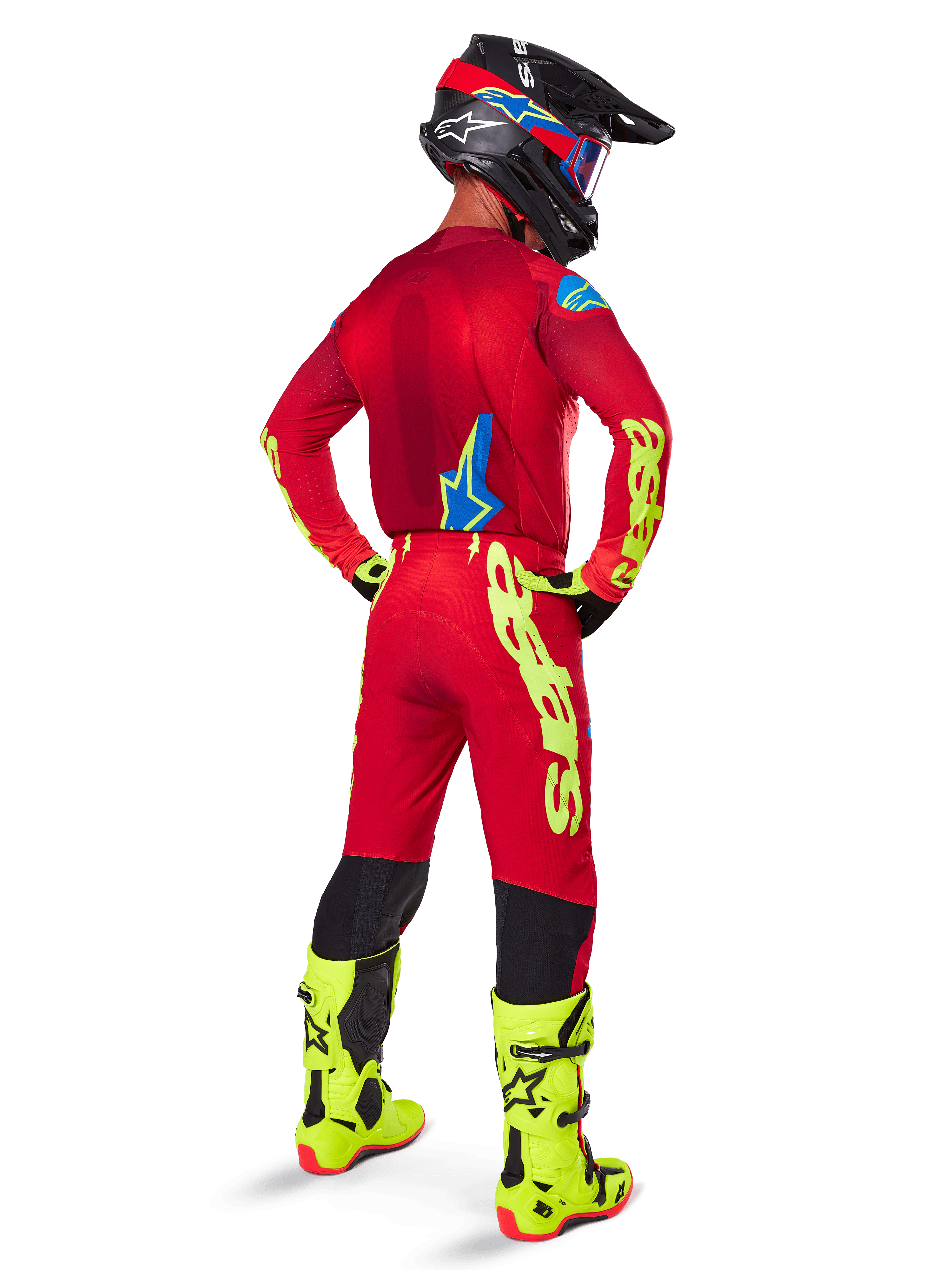 Pilote de motocross vu de dos portant le maillot Alpinestars 2025 Supertech Maker, rouge vif et jaune fluo, pantalon assorti avec marquage jaune, bottes jaune fluo et casque noir et rouge, tenue coordonnée pour la course tout-terrain de niveau professionnel