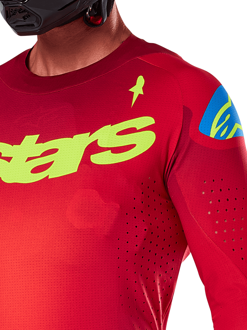Maillot Alpinestars Supertech Maker 2025, maillot de motocross, rouge vif et jaune fluo, vue rapprochée montrant les perforations découpées au laser, marquage Alpinestars jaune sur la poitrine, détail bleu sur l'épaule, tissu en maille extensible et respirant