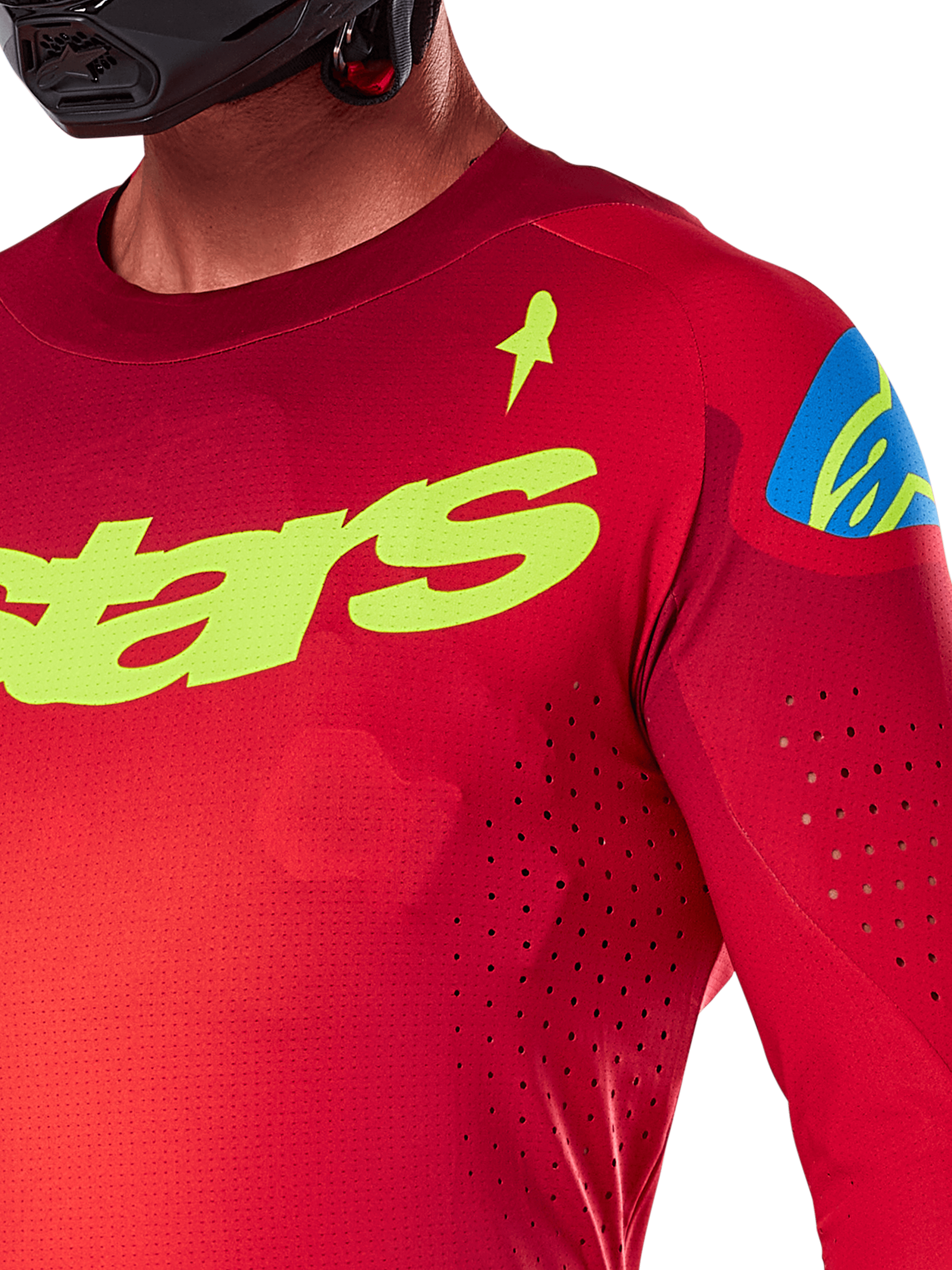 Maillot Alpinestars Supertech Maker 2025, maillot de motocross, rouge vif et jaune fluo, vue rapprochée montrant les perforations découpées au laser, marquage Alpinestars jaune sur la poitrine, détail bleu sur l'épaule, tissu en maille extensible et respirant