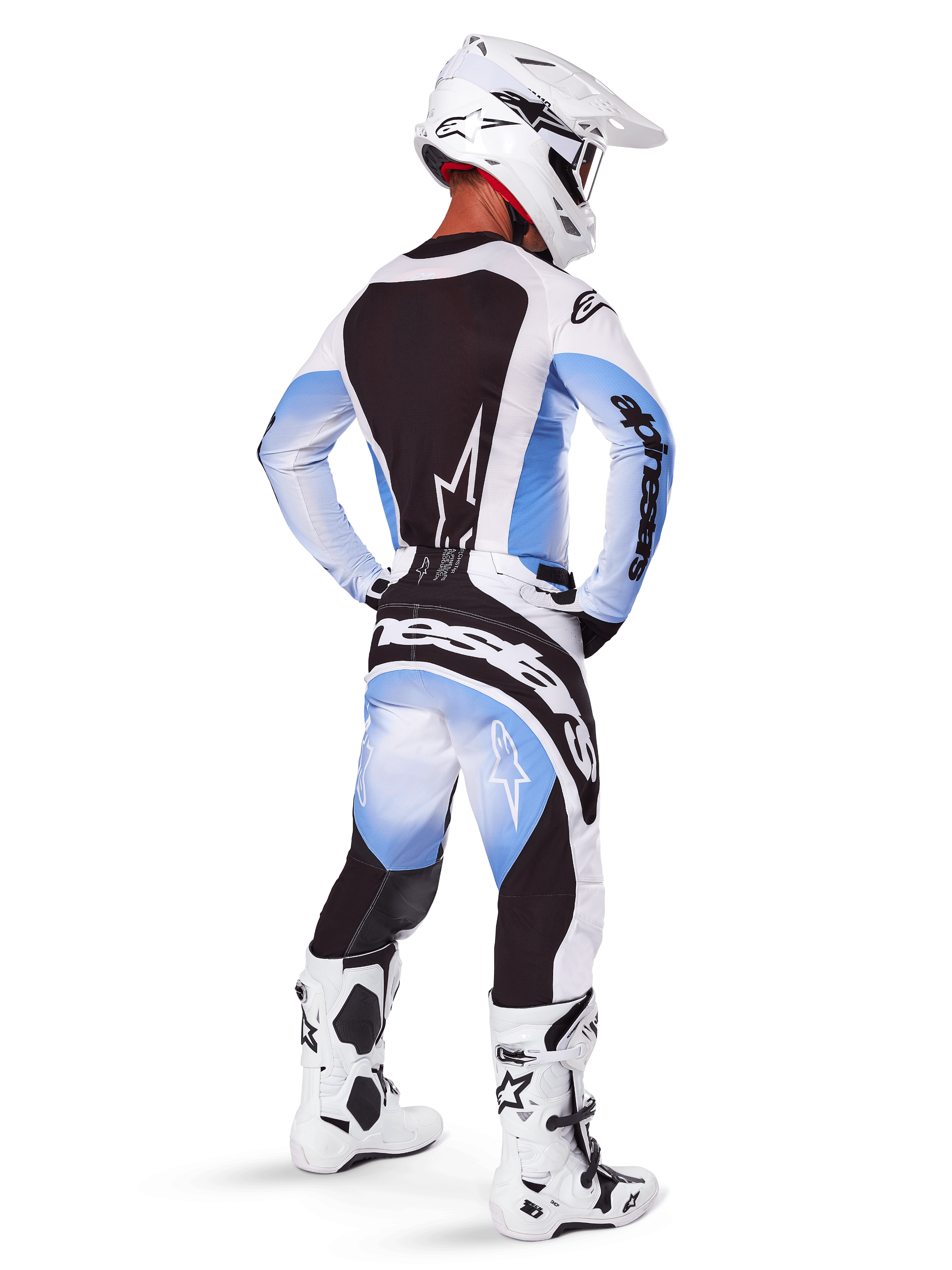 Pilote de motocross portant un équipement de course complet, ensemble Techstar Melt 2025, maillot blanc et bleu clair avec panneau arrière noir, pantalon assorti avec dégradé bleu et accents noirs, casque blanc, bottes blanches et noires, tenue coordonnée pour la course tout-terrain