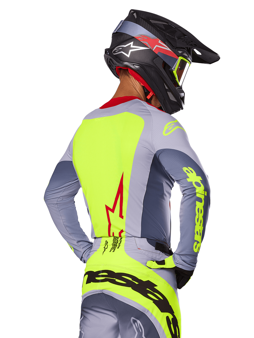 Maillot Alpinestars Techstar Melt 2025, Rouge Vif Gris, vue arrière d'un pilote de motocross portant une tenue de course grise et jaune fluo, logo étoile rouge dans le dos, casque noir et rouge assorti, équipement tout-terrain haute performance