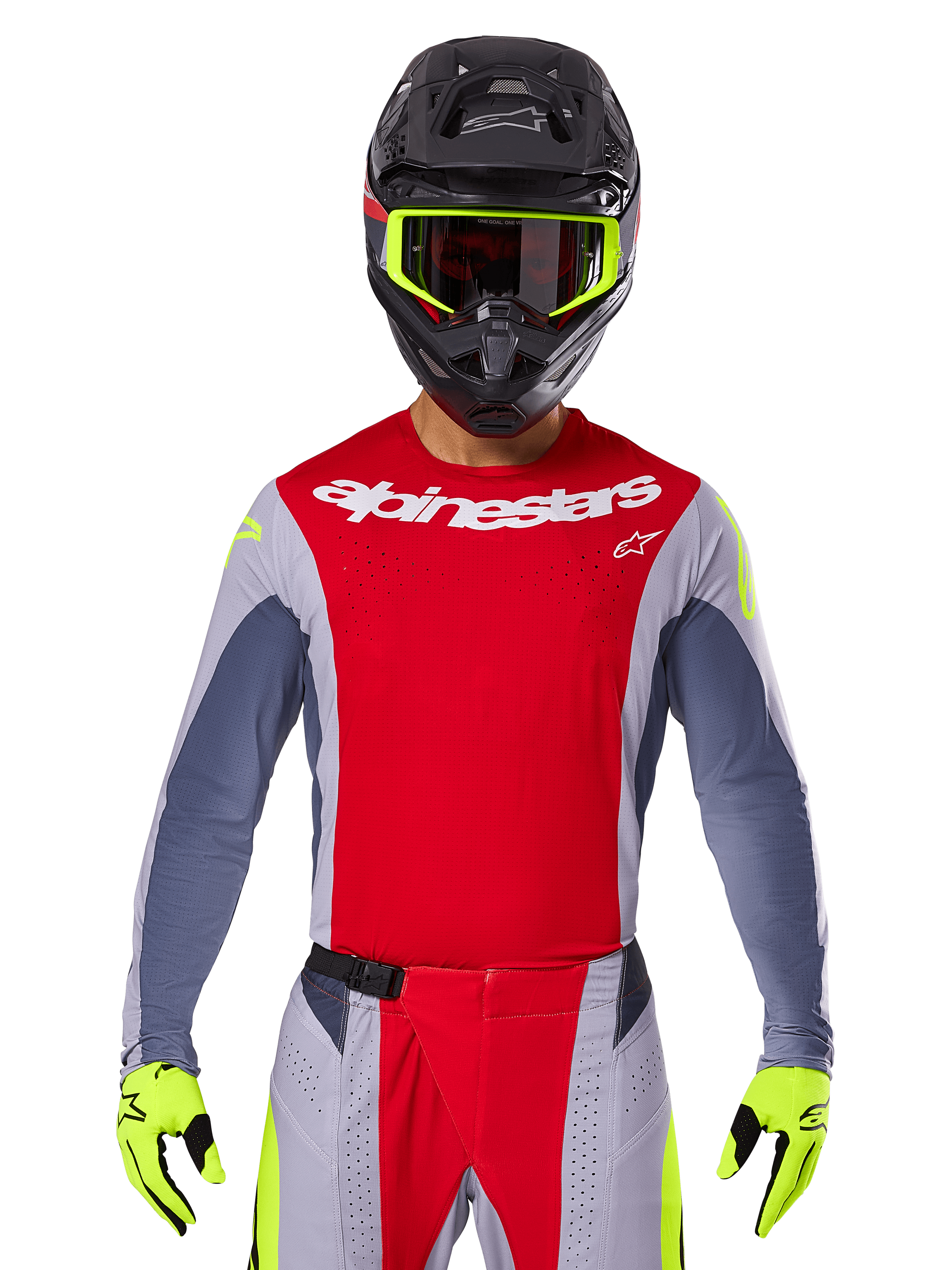 Pilote de motocross portant le maillot Techstar Melt 2025 et le pantalon assorti, rouge vif et gris avec logo Alpinestars blanc, casque noir avec lunettes jaune fluo, gants jaune fluo assortis, équipement de performance ventilé pour la course tout-terrain
