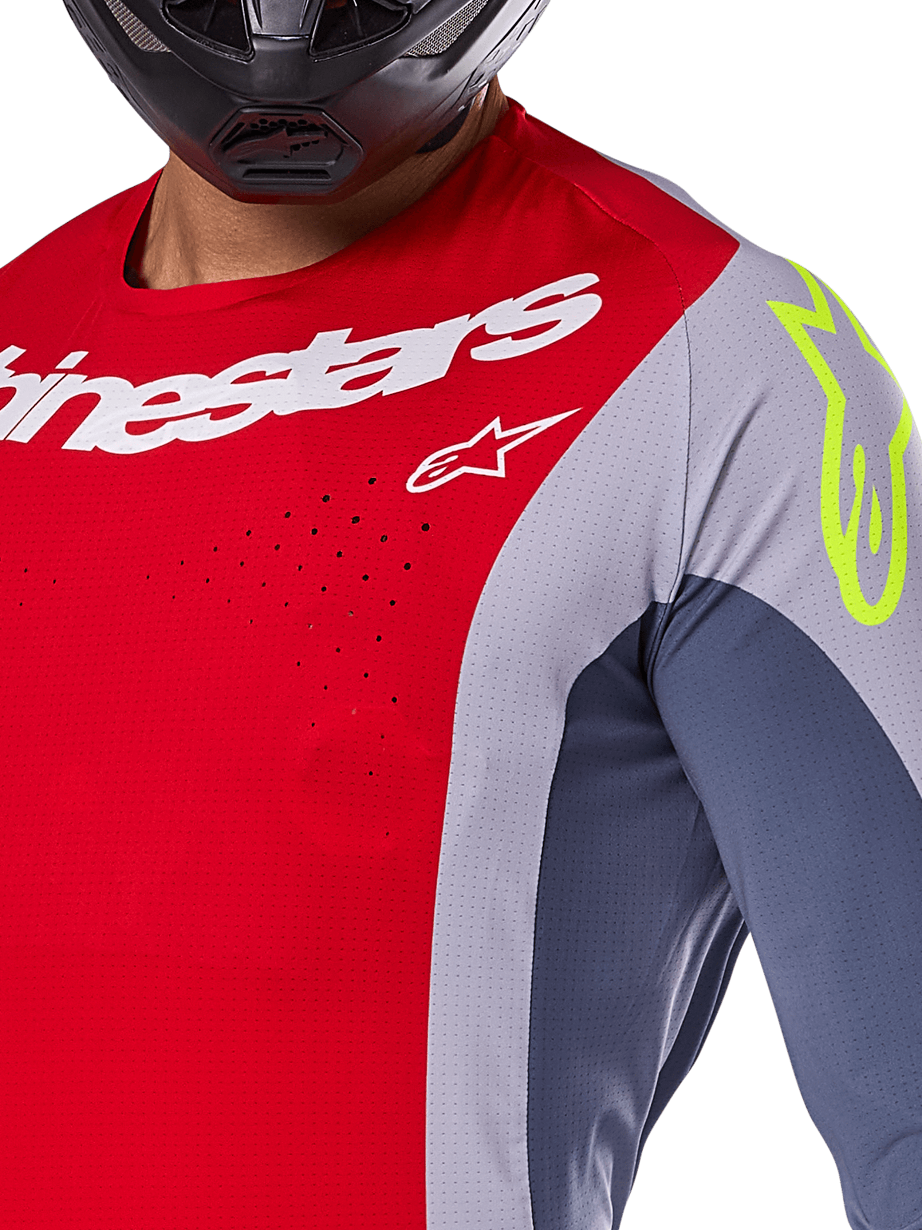 Alpinestars Techstar Melt Jersey 2025, maillot de motocross, rouge vif et gris avec empiècements bleu foncé, logos blanc et jaune fluo sur l'épaule, gros plan montrant les perforations de ventilation découpées au laser et un casque noir