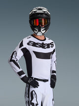 Maillot Alpinestars Racer Riway 2026, maillot de motocross, blanc et noir, orné du logo 'astars' sur la poitrine, porté avec un pantalon blanc et des gants noirs assortis, casque noir et blanc avec lunettes à effet miroir rouge, équipement de course tout-terrain professionnel