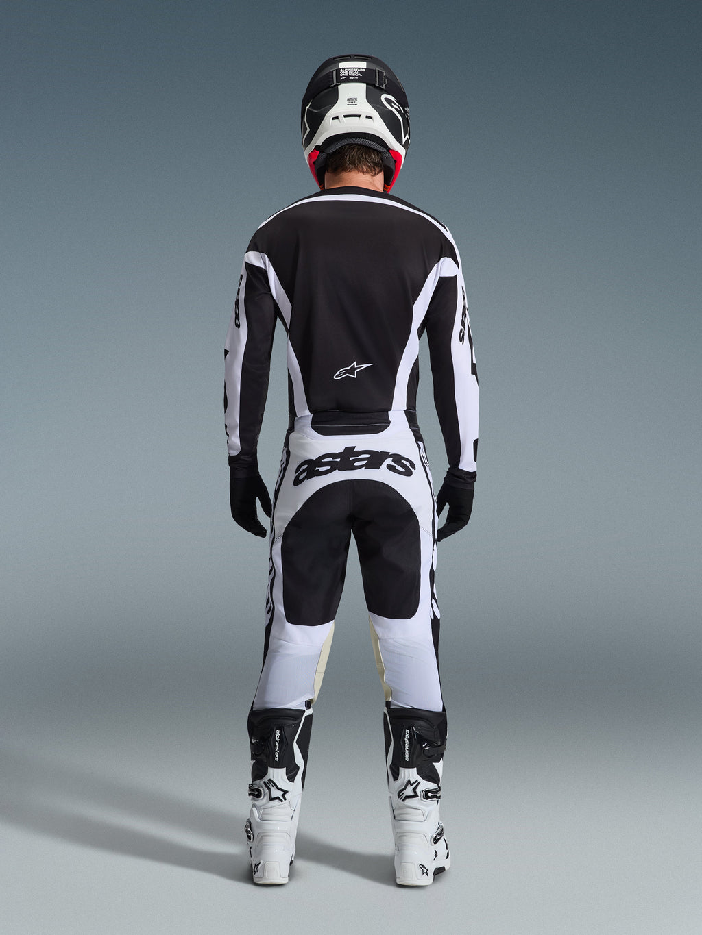 Rear view of a motocross rider wearing the 2026 Racer Riway Gear Set in Black and White, featuring a black jersey with white accents, white pants with bold 'astars' branding on the seat, black helmet, white boots, and black gloves, complete professional off-road racing outfit.