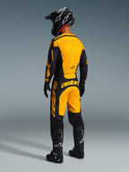 Motocross rider wearing complete racing gear, Alpinestars 2026 Racer Riway Jersey in Yellow and Black, matching yellow and black pants, black helmet, black gloves, and black boots, rear view of coordinated off-road outfit
