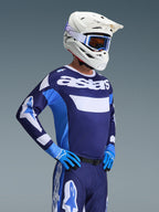 Set d'équipement Alpinestars 2026 Racer Riway, pilote de motocross portant un maillot bleu marine et bleu clair avec logo 'astars' blanc, pantalon bleu marine assorti avec accents blancs, casque blanc avec lunettes bleues et gants bleus, tenue professionnelle complète pour la course tout-terrain