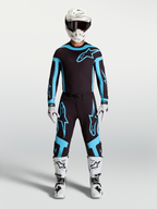 Alpinestars ensemble Supertech Vesta et maillot, tenue de motocross pour homme, noir et turquoise avec bottes et casque blancs, équipement de course tout-terrain.