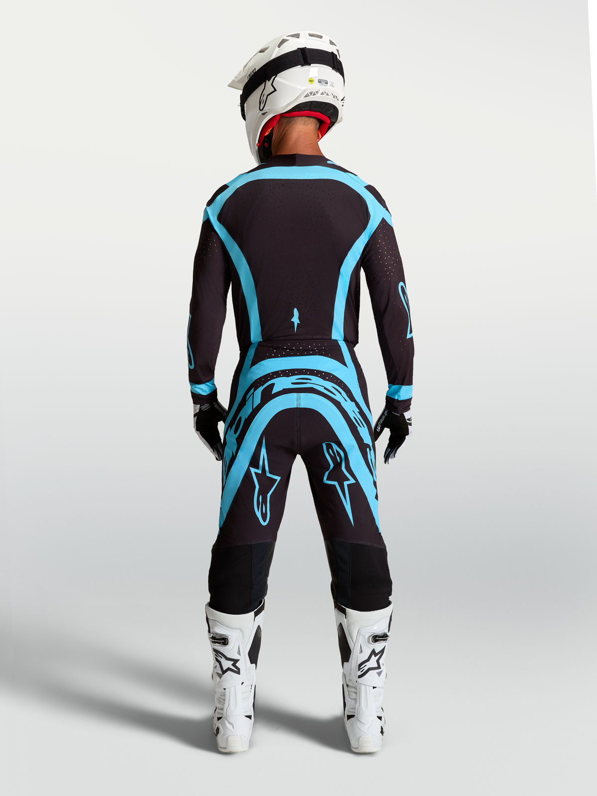 Alpinestars Supertech Vesta, ensemble de motocross pour homme, noir et bleu turquoise, vue de dos montrant le maillot et le pantalon avec coupe athlétique, idéal pour la compétition tout-terrain