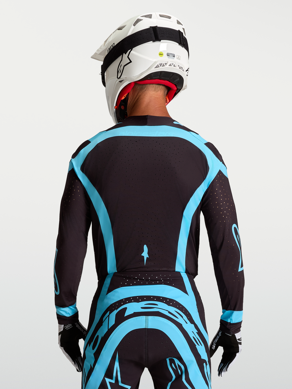 Maillot Supertech Vesta Alpinestars, maillot de moto-cross pro pour homme, noir et turquoise, vue de dos, maille extensible et perforations laser pour la ventilation.
