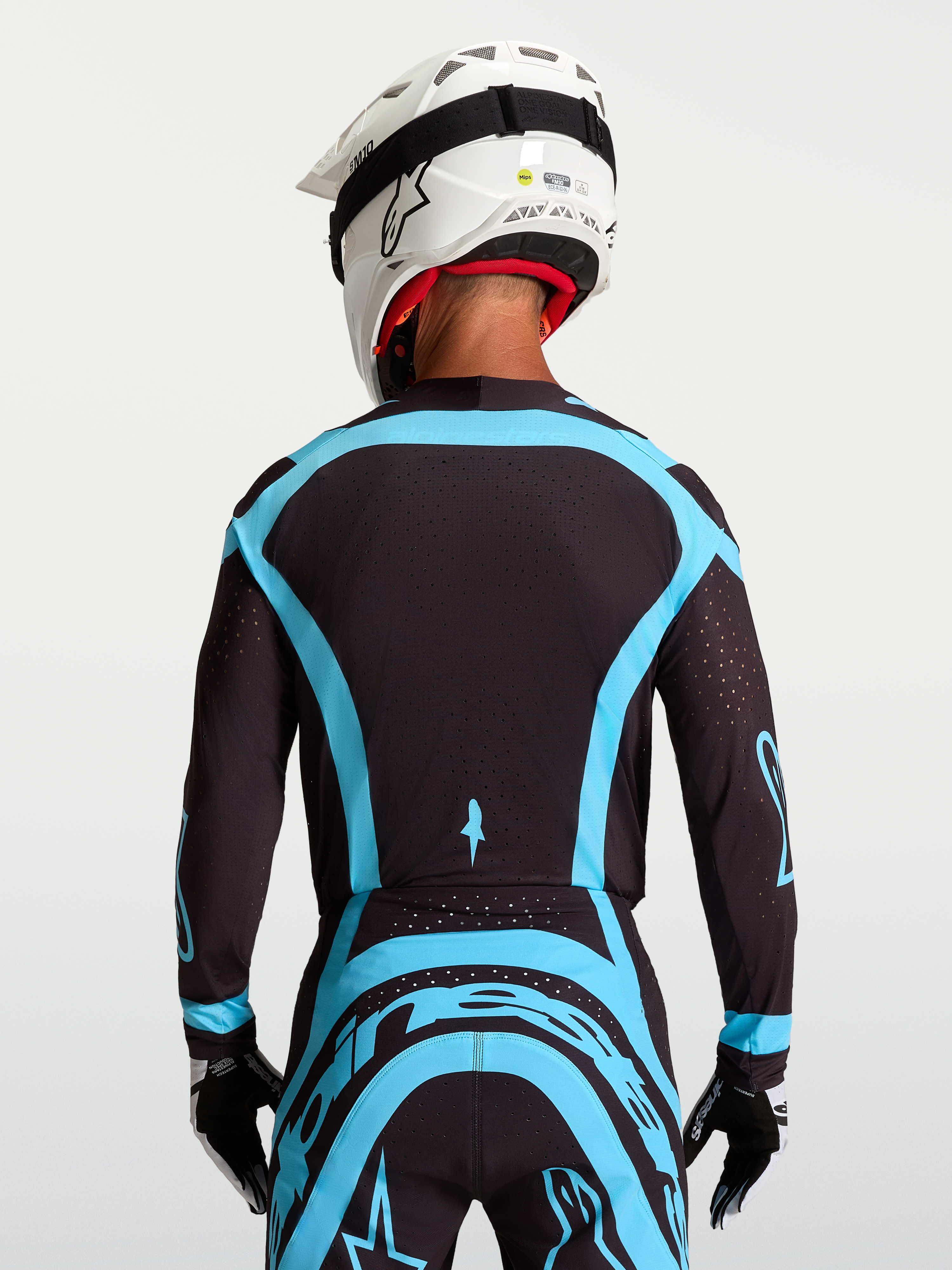 Maillot Supertech Vesta Alpinestars, maillot de moto-cross pro pour homme, noir et turquoise, vue de dos, maille extensible et perforations laser pour la ventilation.