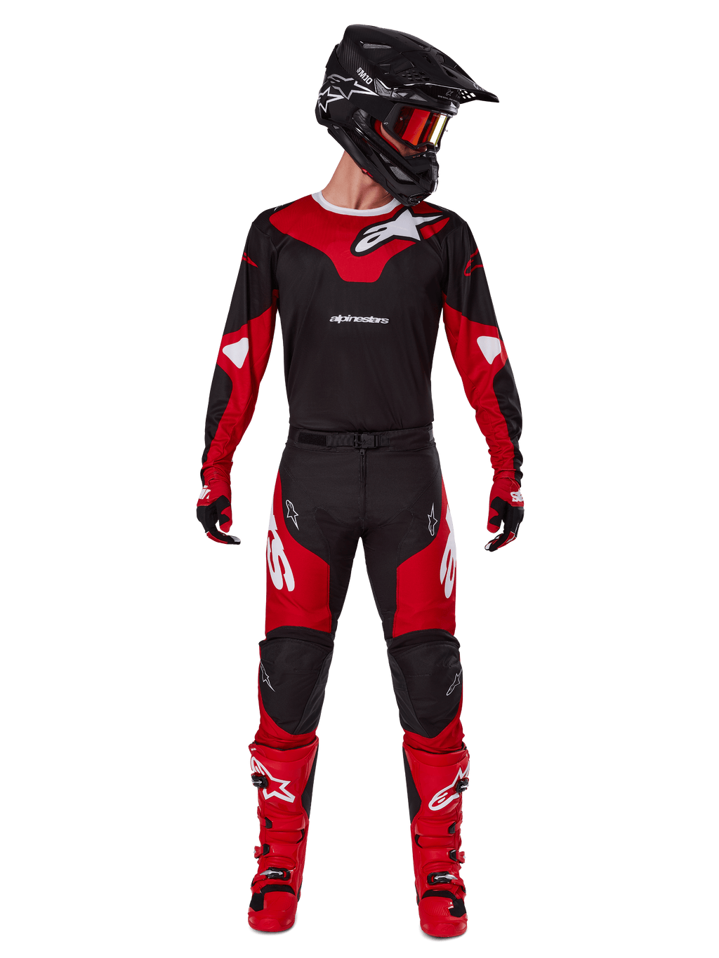 Pilote de motocross portant la tenue Alpinestars 2025 Racer Veil, maillot noir et rouge vif avec logo Alpinestars blanc, pantalon de motocross assorti, casque noir avec lunettes rouges et bottes rouges, équipement de performance complet pour la conduite tout-terrain