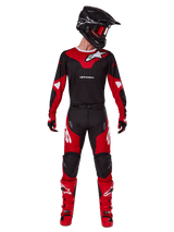 Motocross rider wearing the Alpinestars 2025 Racer Veil gear set, Black and Bright Red jersey with white Alpinestars logo, matching motocross pants, black helmet with red goggles, and red boots, complete performance outfit for off-road riding