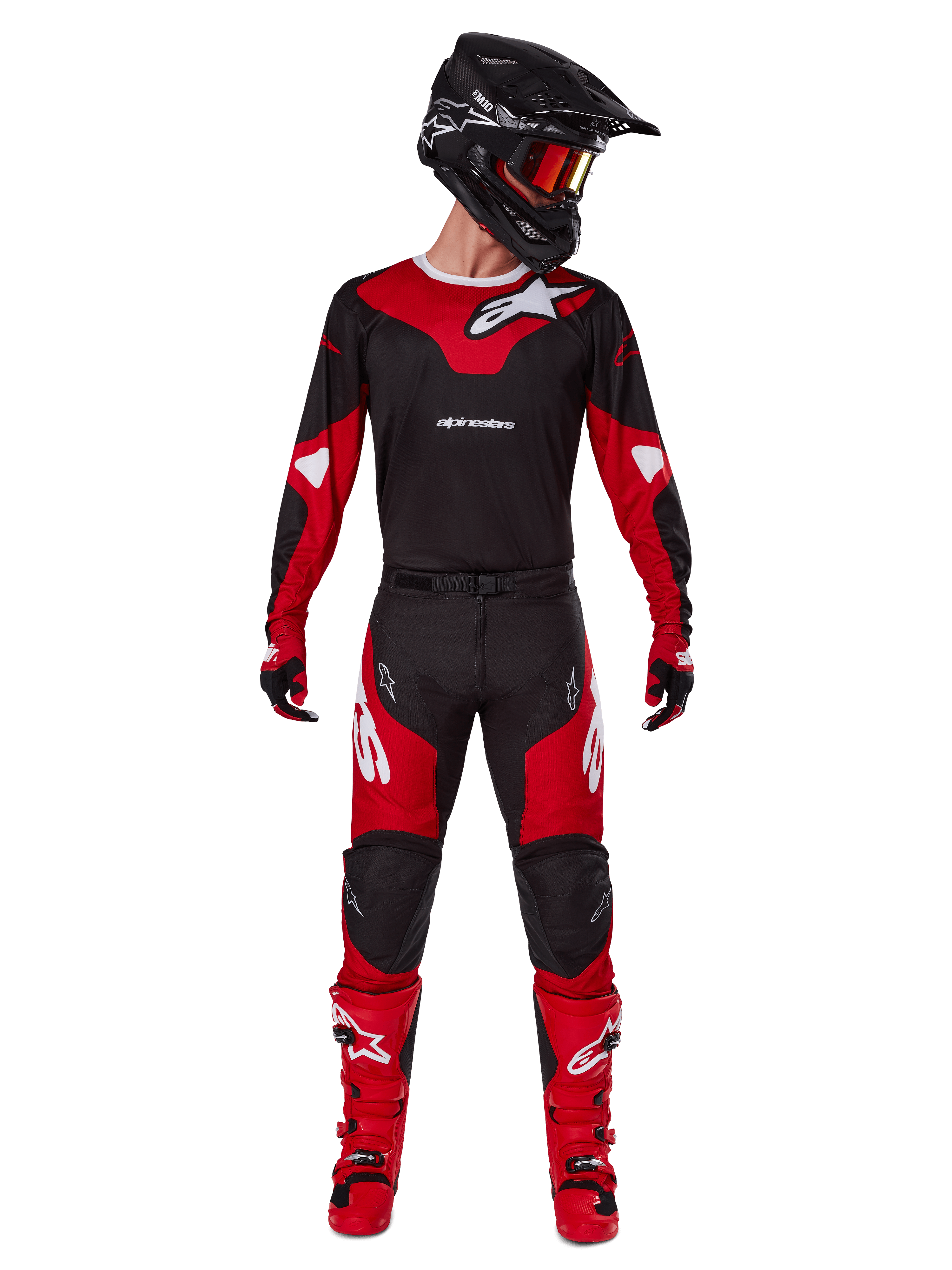 Pilote de motocross portant la tenue Alpinestars 2025 Racer Veil, maillot noir et rouge vif avec logo Alpinestars blanc, pantalon de motocross assorti, casque noir avec lunettes rouges et bottes rouges, équipement de performance complet pour la conduite tout-terrain