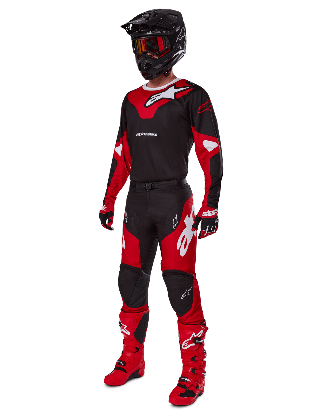 Pilote de motocross portant une tenue de course complète comprenant le maillot Alpinestars 2025 Racer Veil noir et rouge vif, un pantalon assorti, des bottes rouges, un casque noir avec des lunettes rouges et des gants rouges et noirs, look de performance coordonné pour la course tout-terrain