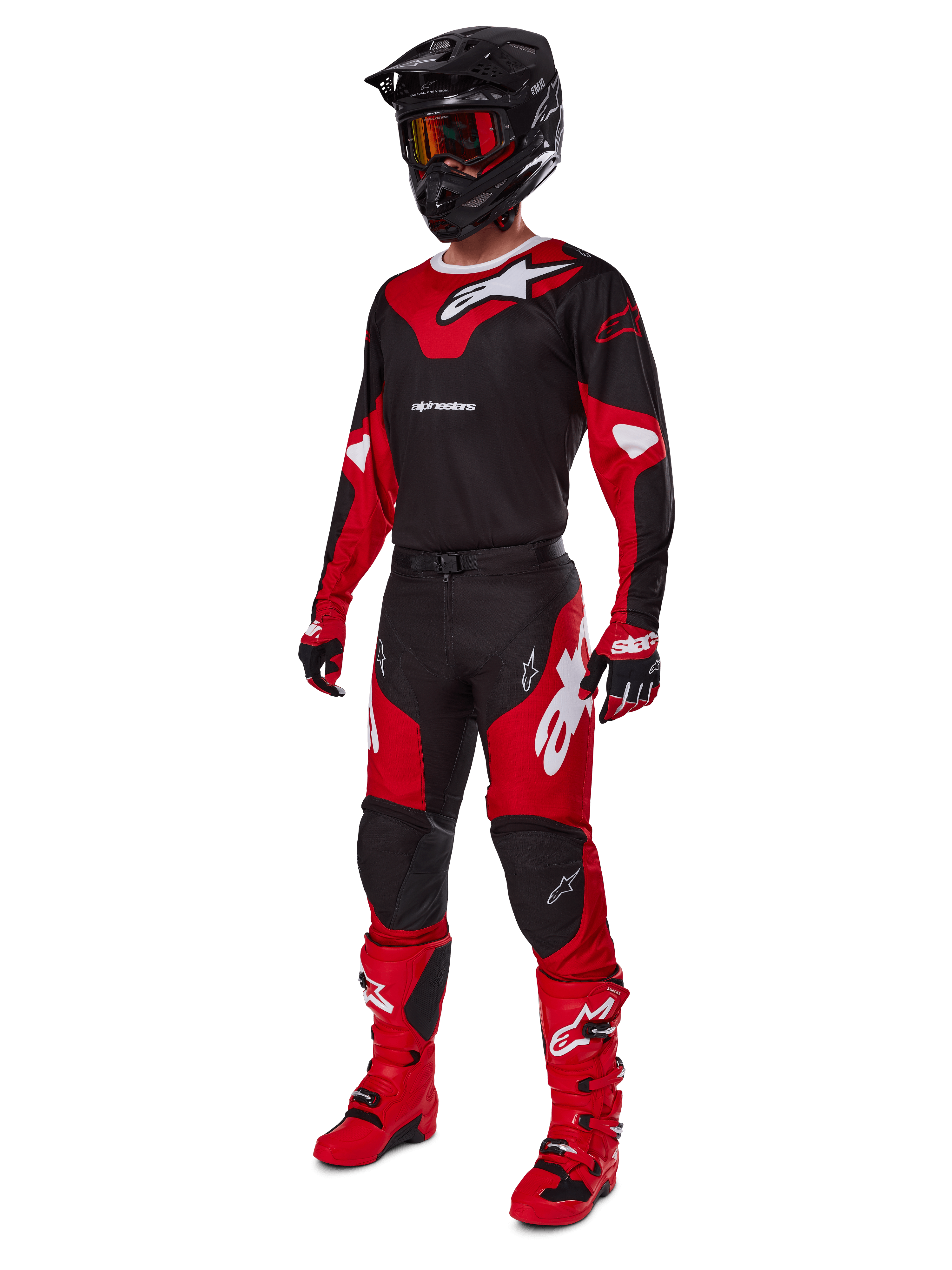 Pilote de motocross portant une tenue de course complète comprenant le maillot Alpinestars 2025 Racer Veil noir et rouge vif, un pantalon assorti, des bottes rouges, un casque noir avec des lunettes rouges et des gants rouges et noirs, look de performance coordonné pour la course tout-terrain