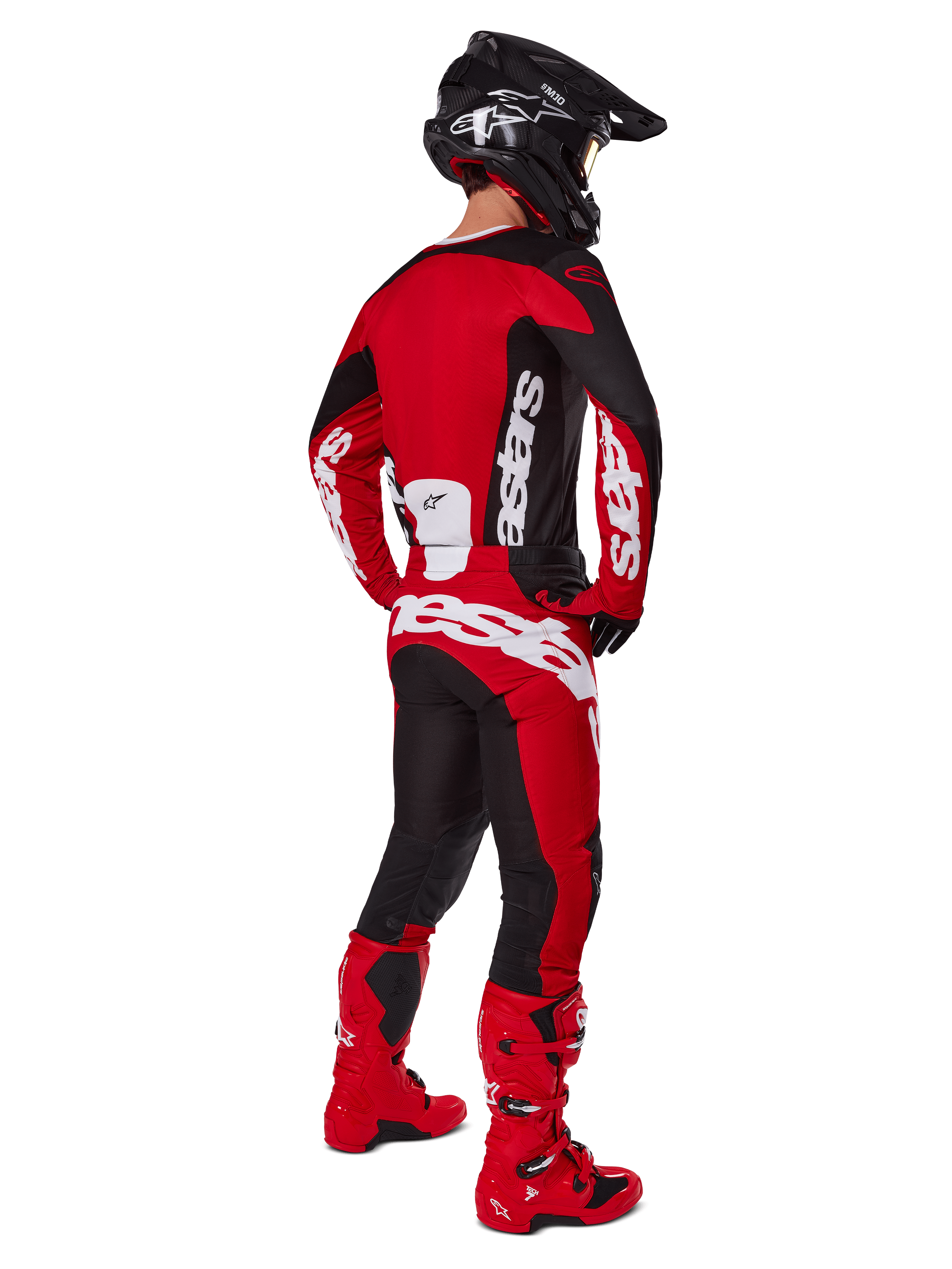 Pilote de motocross de dos portant le maillot Alpinestars Racer Veil 2025 en noir et rouge vif, assorti à un pantalon rouge et noir et des bottes de motocross rouges, avec des logos blancs imposants, idéal pour la performance tout-terrain