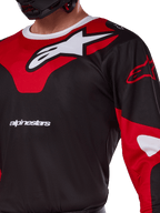 Maillot Alpinestars Racer Veil 2025, maillot de motocross, noir et rouge vif, gros plan présentant un grand logo Astars blanc sur un empiècement de poitrine rouge, texte de la marque blanc et tissu technique évacuant l'humidité.