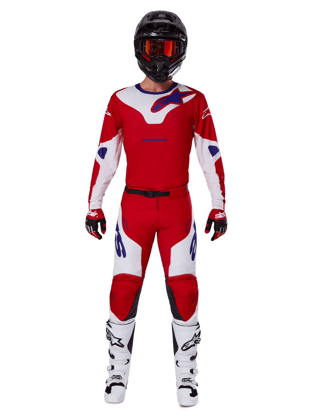 Pilote de motocross portant l'ensemble Alpinestars Racer Veil 2025, maillot et pantalon rouge vif et blanc avec accents bleus, casque noir avec lunettes rouges, bottes blanches et gants rouges et noirs, tenue coordonnée pour la course tout-terrain
