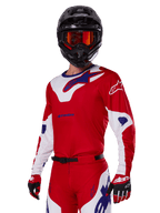 Ensemble d'équipement Alpinestars Racer Veil 2025, pilote de motocross portant un maillot et un pantalon de course rouges, blancs et bleus, casque noir avec lunettes miroir orange, gants rouges et blancs, équipement tout-terrain haute performance avec logos distinctifs
