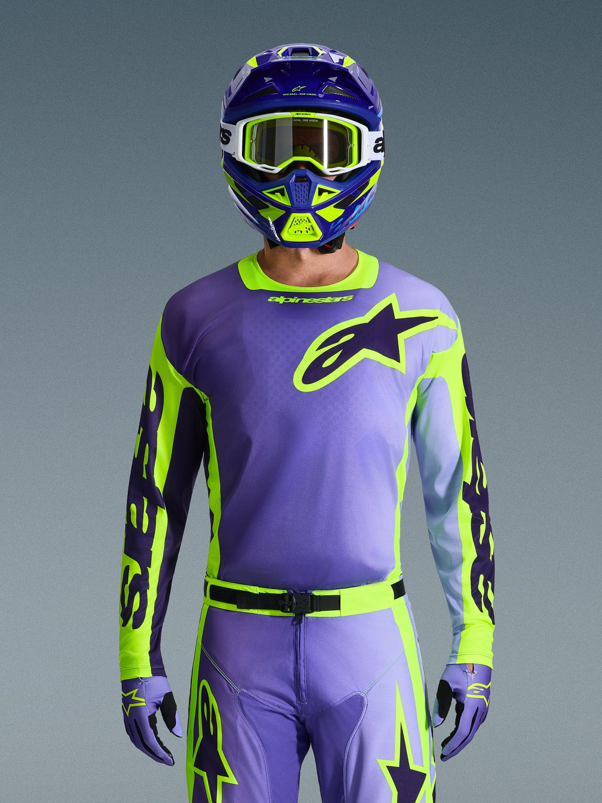 Maillot Alpinestars Racer Portl 2026, maillot de motocross, violet et jaune fluo, porté avec un pantalon, des gants et un casque assortis, arborant un grand logo étoile Alpinestars sur la poitrine, photo en studio sur fond gris.