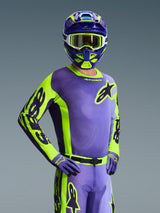 Motocross rider wearing 2026 Racer Portl Jersey, Purple and Yellow Fluo, matching purple and yellow helmet with white goggles, purple and yellow gloves, coordinated full gear set for off-road racing