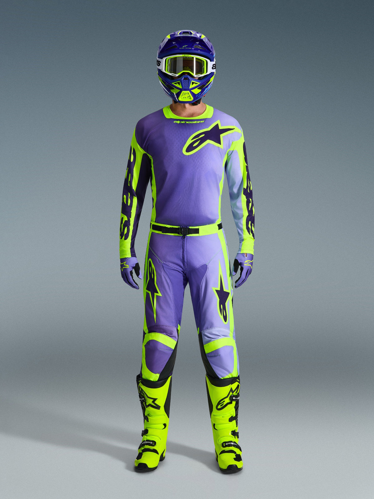 Maillot Alpinestars Racer Portl 2026, violet et jaune fluo, porté dans le cadre d'un ensemble de motocross complet avec pantalon, casque et bottes jaune fluo éclatant, tenue de course tout-terrain professionnelle