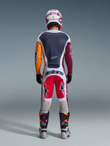 Pilote de motocross de dos portant une tenue de course complète, maillot Racer Portl 2026 rouge, gris clair et vert foncé avec manches asymétriques orange et bordeaux, pantalon assorti blanc et rouge, casque blanc avec lunettes violettes, bottes blanches et noires, tenue coordonnée pour la course tout-terrain