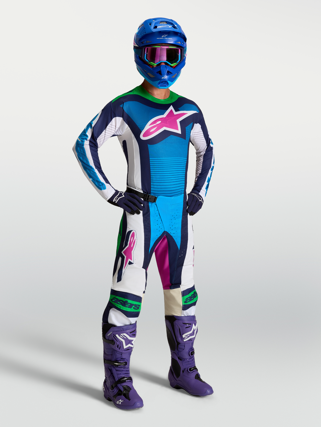 Alpinestars Maillot Techstar Maven, maillot de motocross bleu et blanc avec logo rose, pour homme, coupe athlétique et tissu respirant, porté par un pilote avec équipement tout-terrain.