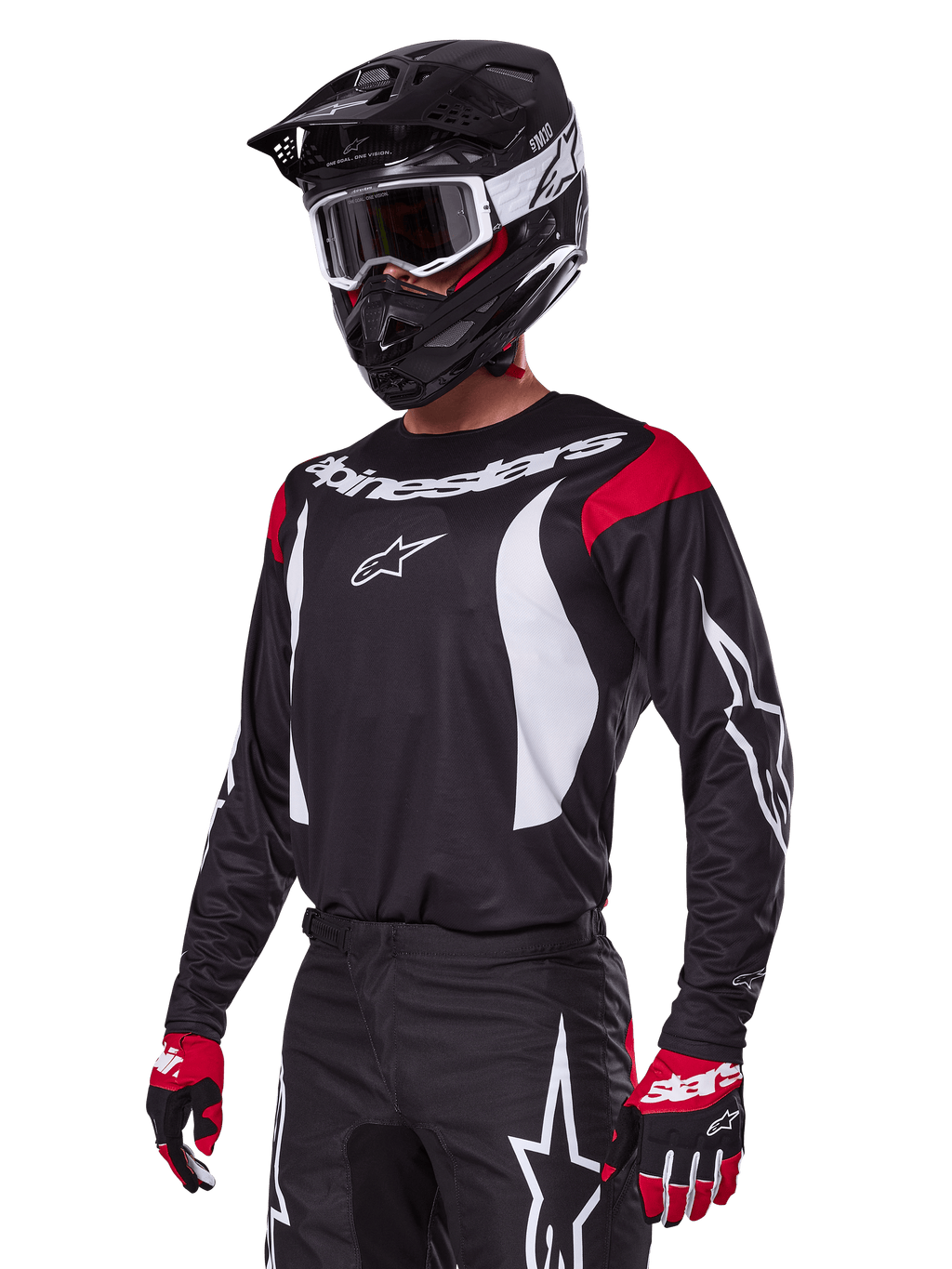 Pilote de motocross portant l'ensemble d'équipement Alpinestars Fluid Haul 2025, maillot noir avec empiècements rouges aux épaules et graphismes blancs, pantalon noir assorti avec logos étoiles blancs, gants rouges et noirs, casque noir avec détails blancs et lunettes, tenue de motocross coordonnée.