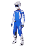 Pilote de motocross portant l'ensemble d'équipement complet 2025 Fluid Haul, maillot et pantalon bleu et blanc avec logo Alpinestars, casque blanc avec lunettes bleues, bottes blanches et gants bleus, tenue de course coordonnée pour le motocross tout-terrain