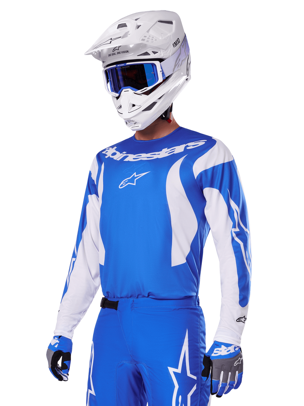 Pilote de motocross portant l'ensemble d'équipement Alpinestars Fluid Haul 2025 bleu et blanc, comprenant un maillot bleu avec détails blancs, un pantalon bleu assorti avec logos étoiles, un casque blanc avec lunettes bleues et des gants bleus et gris coordonnés, tenue de course tout-terrain complète