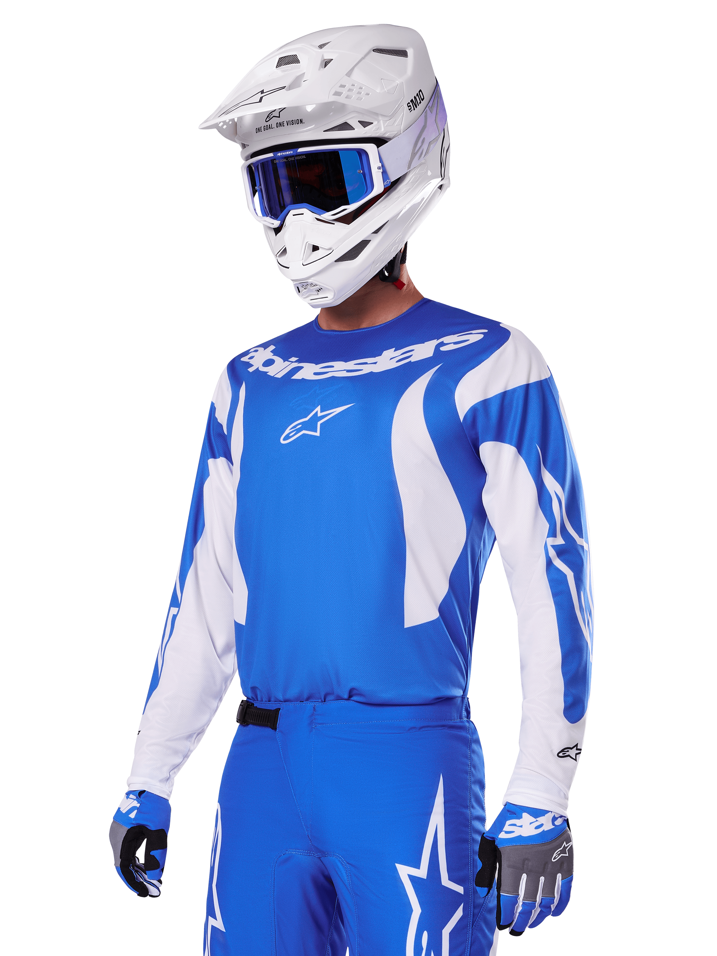 Pilote de motocross portant l'ensemble d'équipement Alpinestars Fluid Haul 2025 bleu et blanc, comprenant un maillot bleu avec détails blancs, un pantalon bleu assorti avec logos étoiles, un casque blanc avec lunettes bleues et des gants bleus et gris coordonnés, tenue de course tout-terrain complète