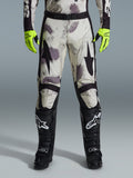 Alpinestars 2026 Racer Lahnd Pants, Motocross Pants, Sand Camo pattern with gray and purple abstract graphics, worn with neon yellow gloves and black boots, featuring black star logos on the thighs and a black waist belt, durable off-road racing gear