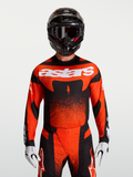 Alpinestars Techstar Swan, maillot de motocross rouge cardinal et noir, coupe athlétique, porté par un mannequin.