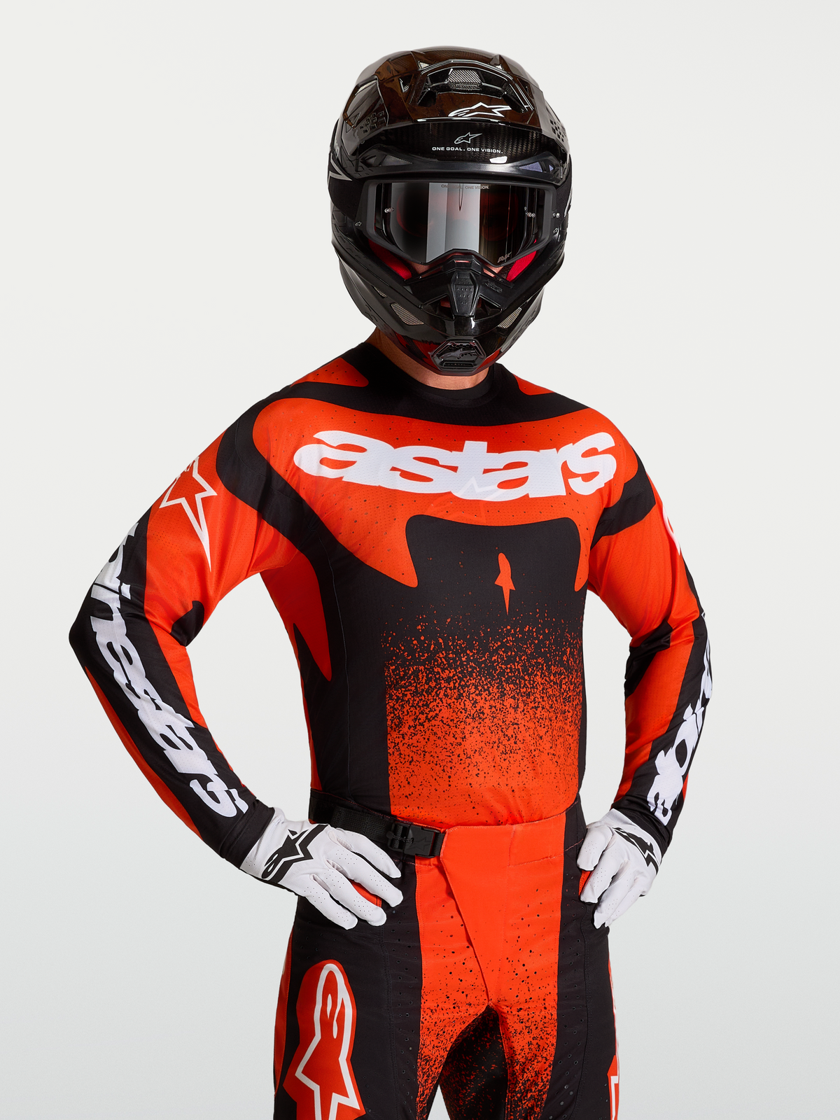 Maillot Alpinestars Techstar Swan, maillot de motocross pour homme, rouge cardinal, noir et blanc, coupe athlétique de course, porté par un mannequin avec un casque et des gants, tissu perforé au laser pour une ventilation optimale
