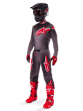 Ensemble d'équipement Alpinestars Supertech Lipan 2025, tenue de motocross complète, maillot gris foncé et rouge avec un grand logo en étoile, pantalon assorti avec des accents rouges et des graphismes d'étoiles, gants rouges et bottes rouge vif avec des boucles blanches, incluant un casque noir mat avec des lunettes rouges.