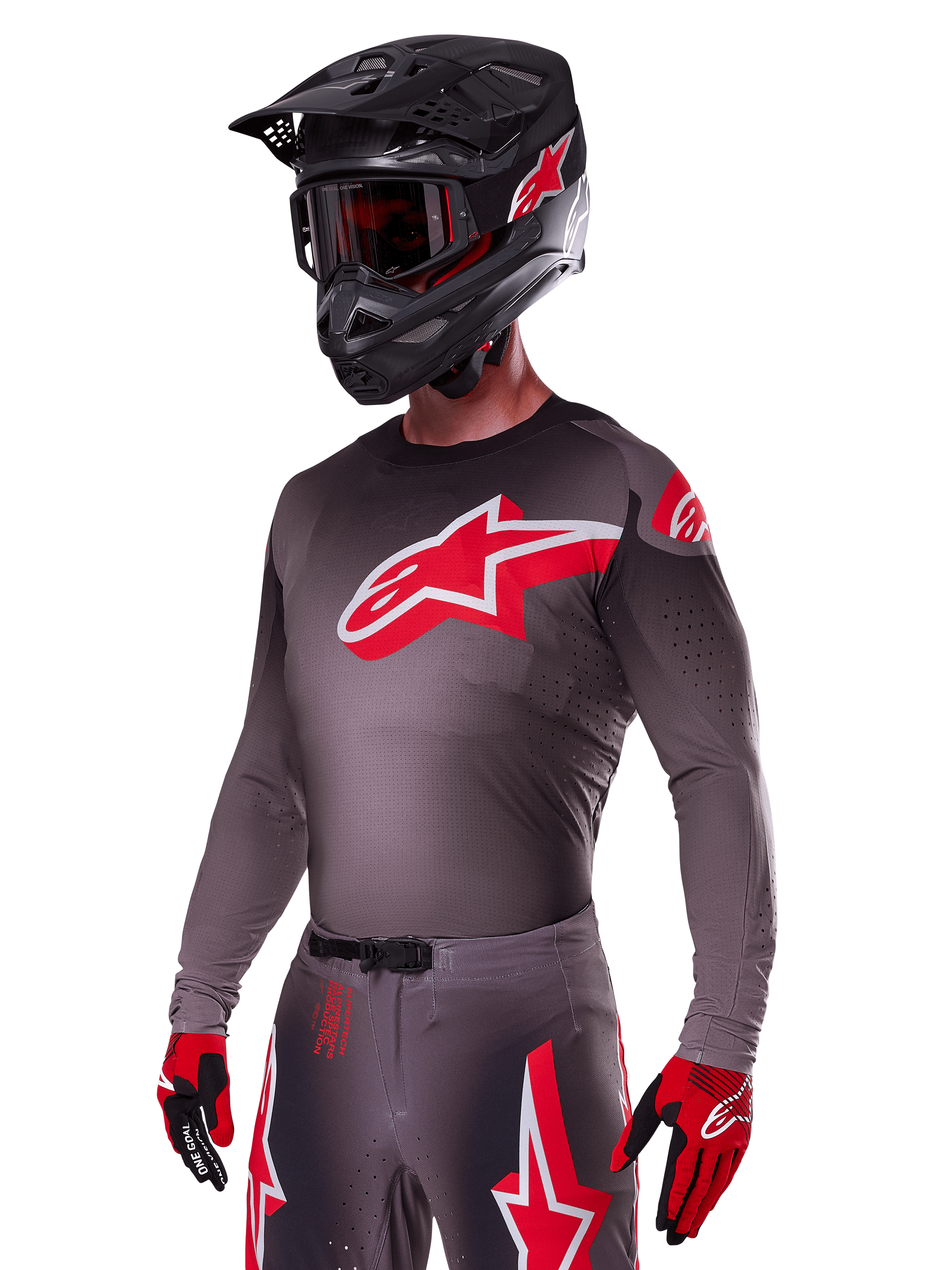 Ensemble d'équipement Alpinestars Supertech Lipan 2025, pilote de motocross portant un maillot et un pantalon gris foncé avec des accents rouges et blancs, doté d'un grand logo Alpinestars rouge sur la poitrine, perforations découpées au laser pour la ventilation, casque noir assorti, lunettes rouges et gants rouges et noirs