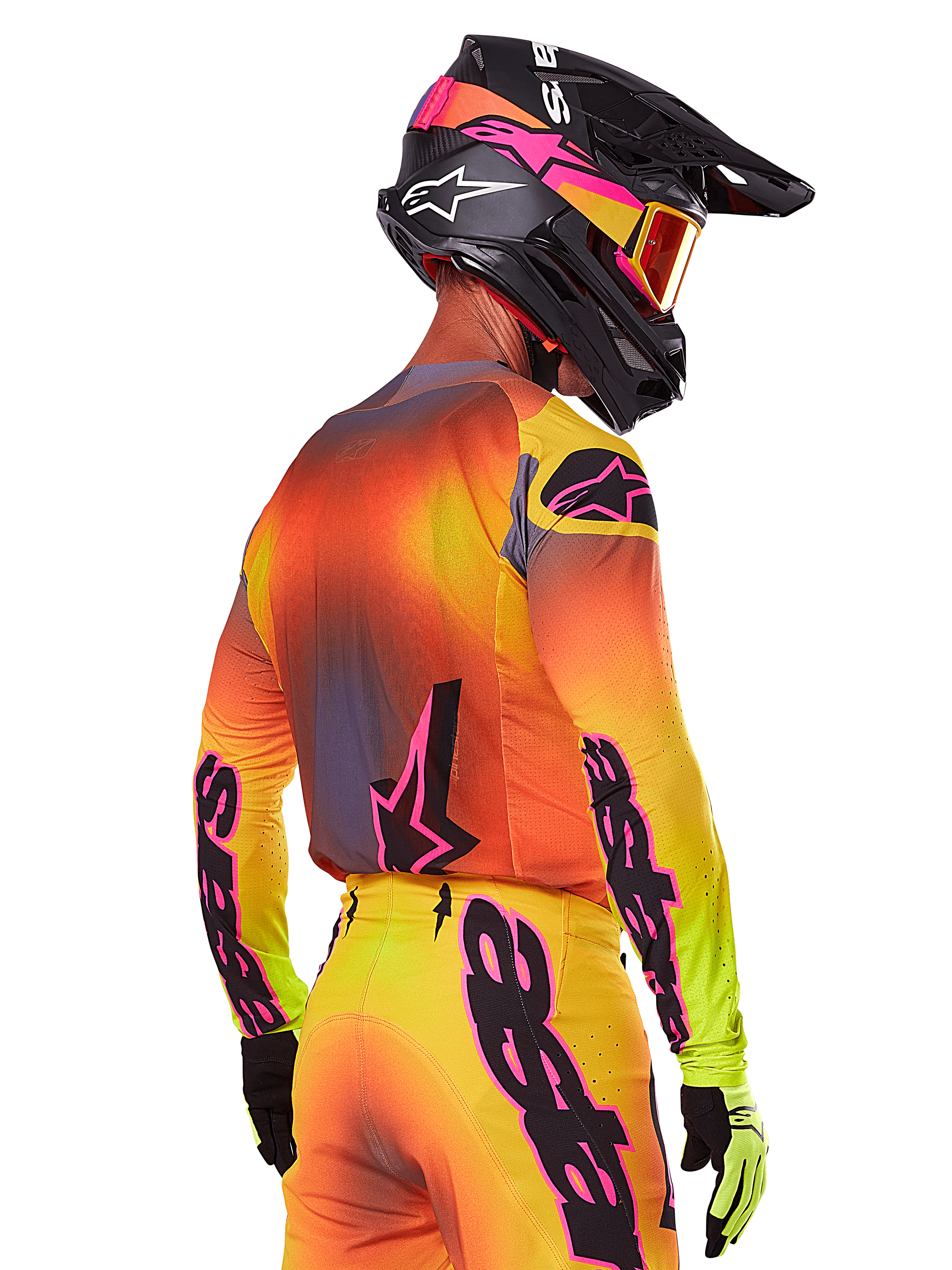 Pilote de motocross vu de trois-quarts arrière portant l'ensemble d'équipement Alpinestars Supertech Lipan 2025, présentant un dégradé jaune, orange et rouge avec des logos noirs et roses, casque noir avec accents roses et lunettes orange, tenue de course tout-terrain professionnelle.
