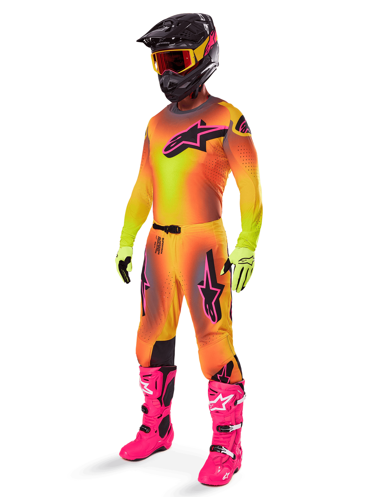 Pilote de motocross portant l'ensemble Supertech Lipan 2025 d'Alpinestars, maillot et pantalon avec dégradé jaune et orange et accents roses, casque noir avec lunettes jaune et rouge, gants jaune vif et bottes rose vif, tenue de course tout-terrain coordonnée