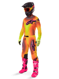 Pilote de motocross portant l'ensemble Supertech Lipan 2025 d'Alpinestars, maillot et pantalon avec dégradé jaune et orange et accents roses, casque noir avec lunettes jaune et rouge, gants jaune vif et bottes rose vif, tenue de course tout-terrain coordonnée