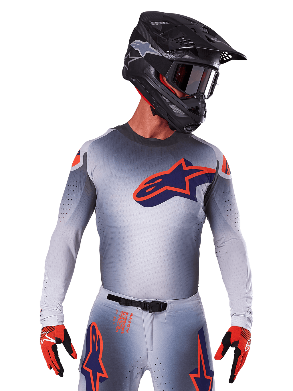 Maillot Alpinestars Supertech Lipan 2025, maillot de motocross, gris avec des accents orange et bleu marine, haut de performance à manches longues avec détails de ventilation perforés, porté avec un casque noir et des gants rouges, design de course épuré