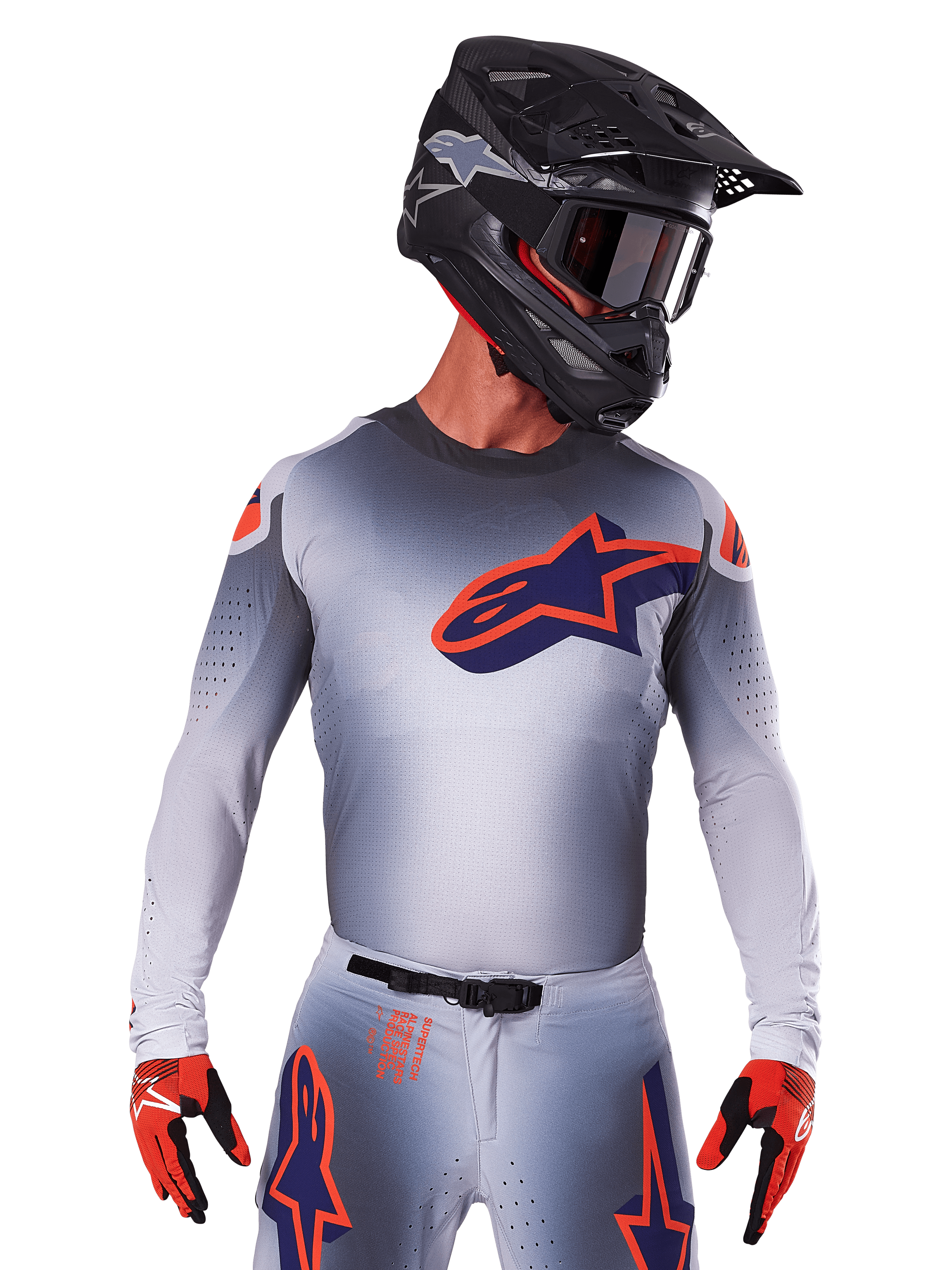 Maillot Alpinestars Supertech Lipan 2025, maillot de motocross, gris avec des accents orange et bleu marine, haut de performance à manches longues avec détails de ventilation perforés, porté avec un casque noir et des gants rouges, design de course épuré