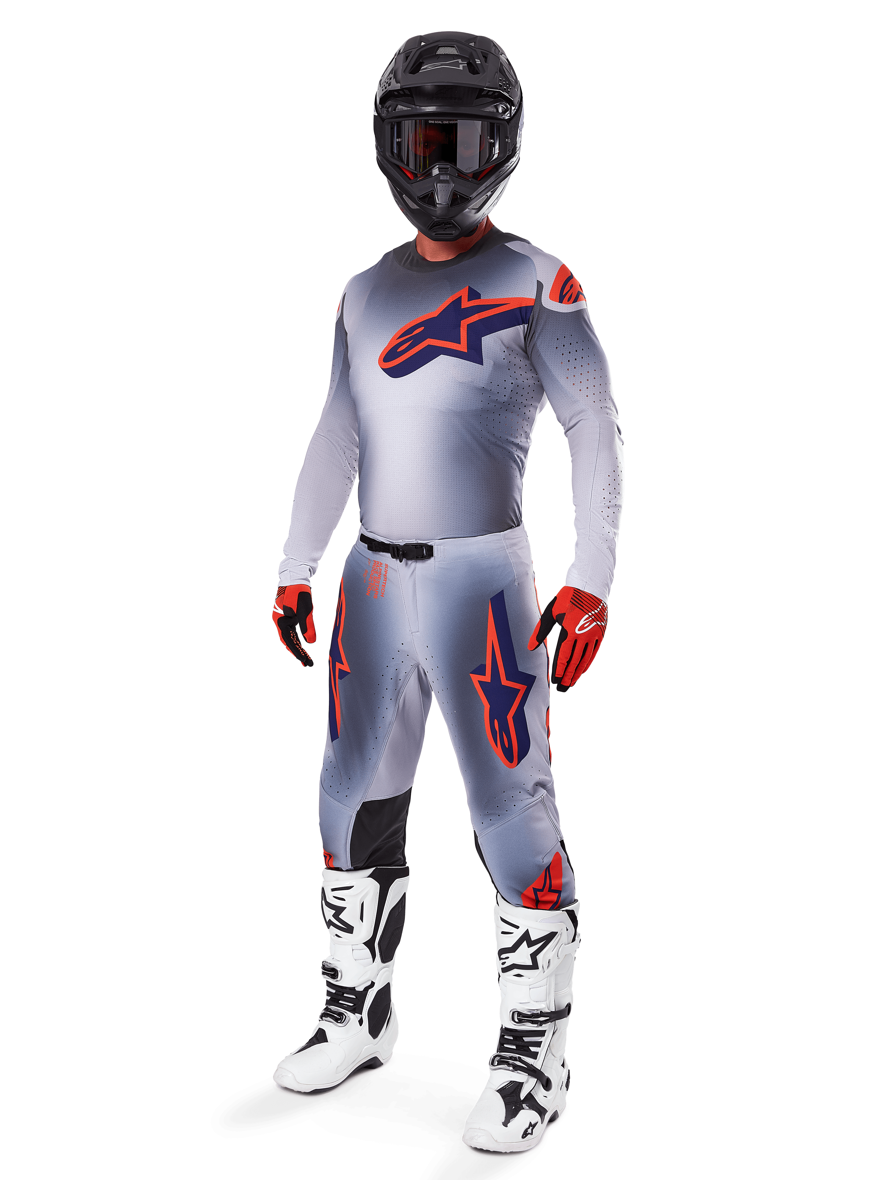 Ensemble d'équipement Alpinestars Supertech Lipan 2025, équipement de motocross, gris avec graphismes d'étoiles orange fluo et bleu marine, porté avec un casque noir, des gants rouges et noirs et des bottes blanches et noires, tenue tout-terrain professionnelle complète au design ventilé