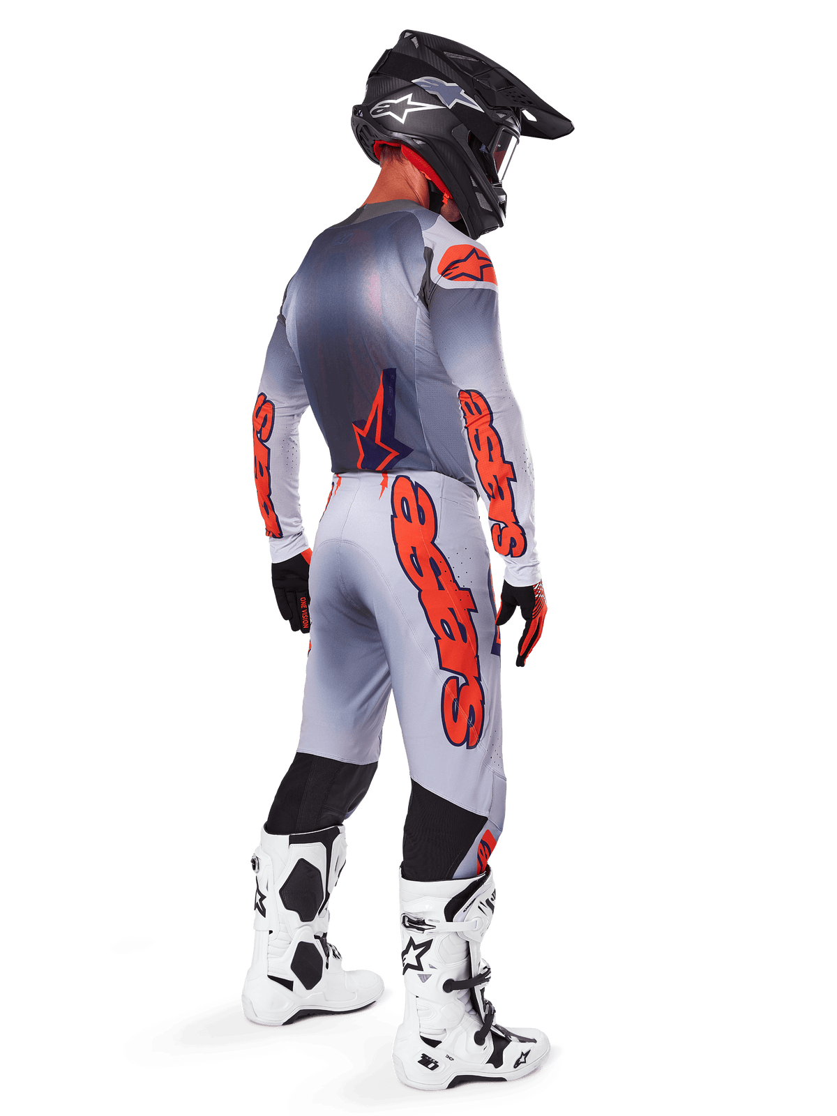 Pilote de motocross de profil arrière portant un maillot Supertech Lipan 2025 et un pantalon assorti en gris et orange fluo, avec le marquage Alpinestars orange vif sur les manches et les jambes, associé à un casque noir et des bottes blanches, tenue professionnelle coordonnée pour la course tout-terrain