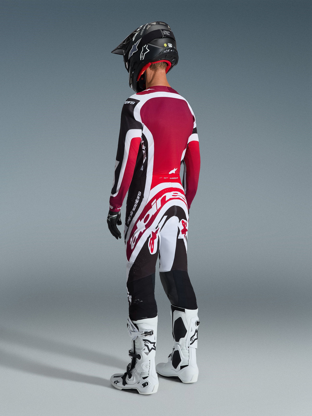 Motocross rider from a rear view wearing the 2026 Supertech AFD Vista Jersey in Black Red and White, matching motocross pants with bold white Alpinestars branding, black helmet, and white and black boots, professional off-road racing gear set